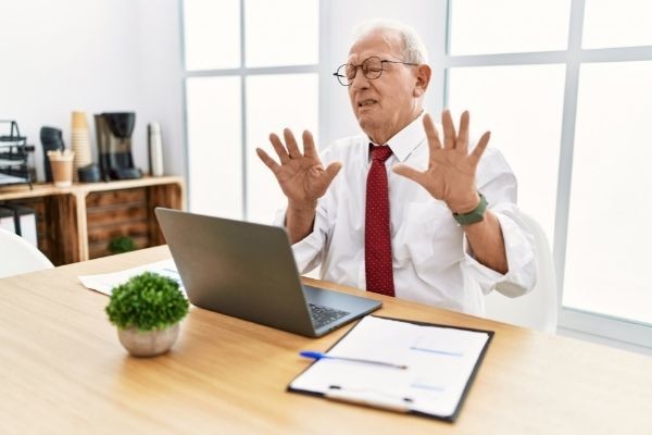 senior man working office using computer disgusted