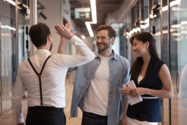 ways-to-say-looking-forward-to-working-with-you-three-workers-standing-office-hallway-highfive