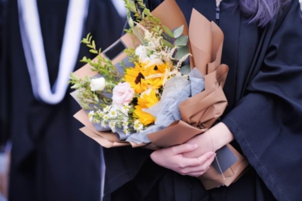 graduates academic dresses holding beautiful flower