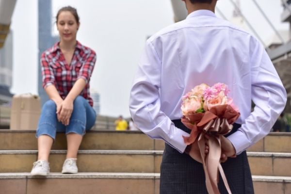 beautiful young couple sitting man send flower on back