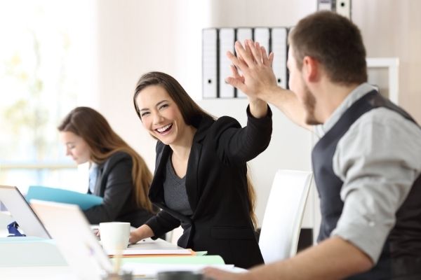 two happy coworkers celebrating success giving high five