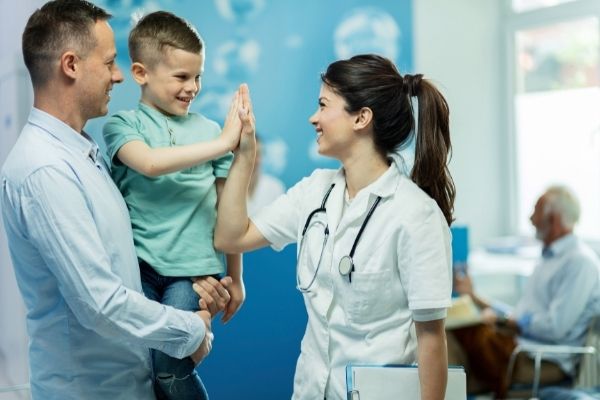 happy female doctor giving high five on young boy