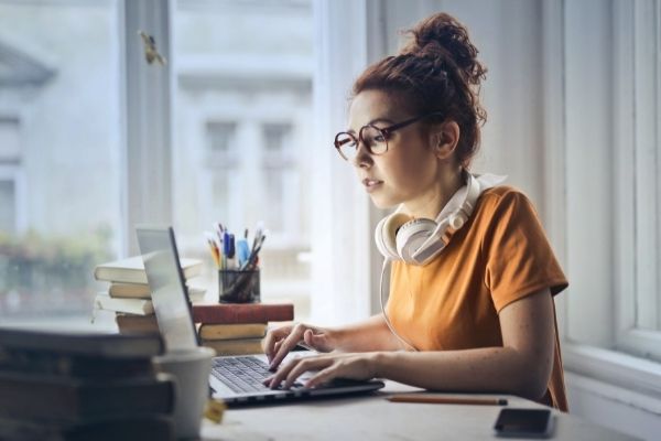 young woman working on laptop wearing glasses