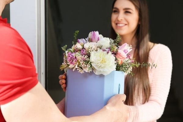 young woman receiving beautiful flowers delivery