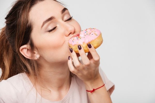 close portrait pleased pretty girl eating donuts
