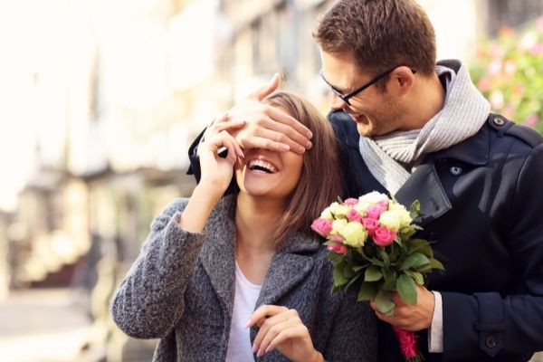 picture young man surprising woman flowers covering eyes