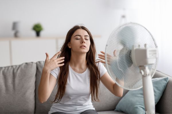 sad young european woman suffering heat in front of a fan