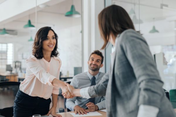smiling young businesswoman shaking hands coworker