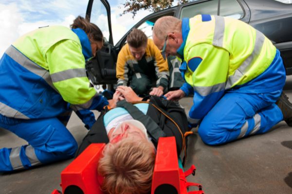 two paramedics fireman working together help accident patient lying on stretcher