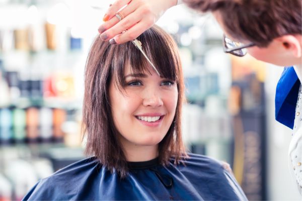 hairdresser cutting woman hair shop