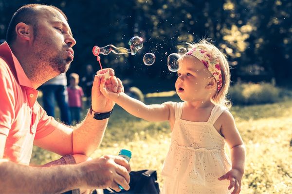 daddy daughter blowing bubbles park
