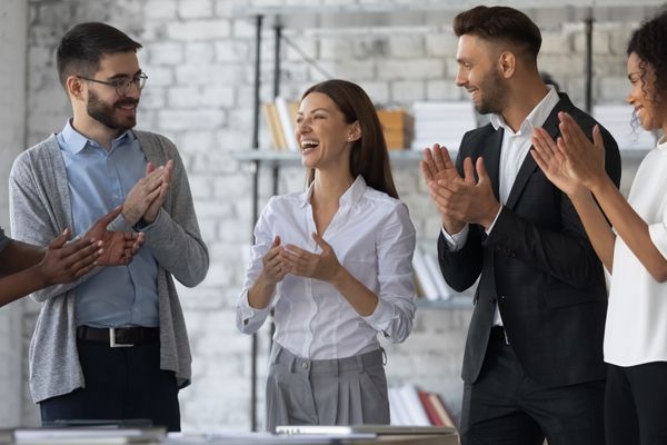 friendly diverse employees congratulating businesswoman clapping