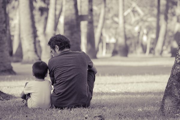 father son sitting on lawn garden monochromatic color