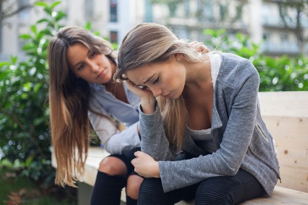 woman comforting sad depressed friend who has a problem