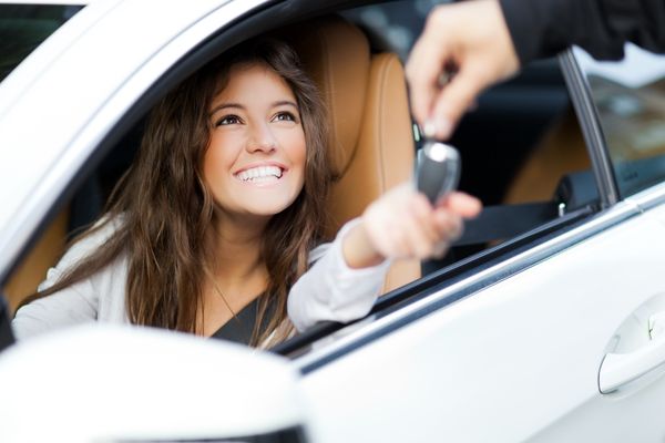 young woman receiving keys her new car