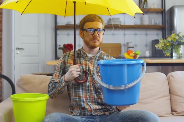 portrait upset young hipster guy glasses umbrella and pail