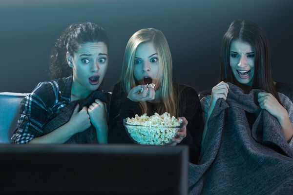 teenage girls watching horror movie popcorn