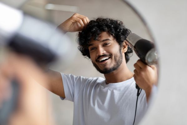 excited indian man using hairdryer after