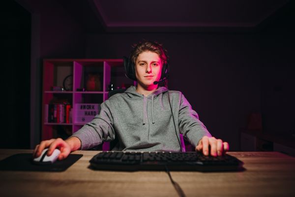 handsome young man casual clothes headset playing computer