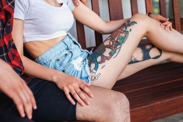 couple on bench tattoo on legs