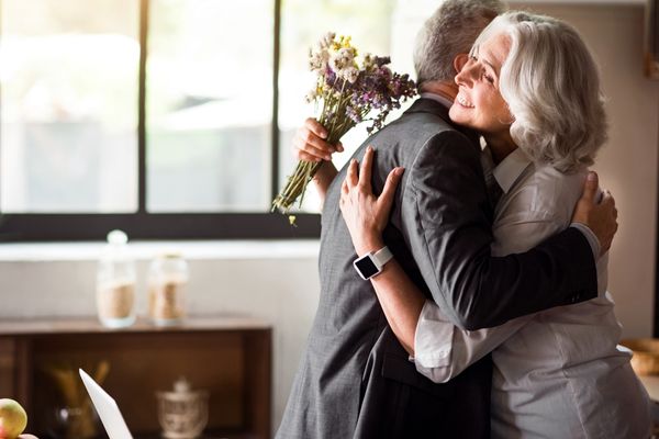 Happy elderly couple hug receive flowers
