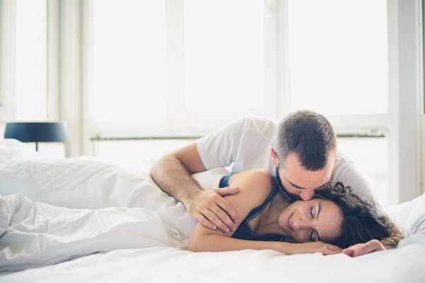 man kissing woman lying on bed