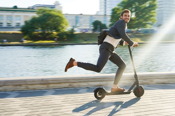 young businessman wearing formal riding electric scooter