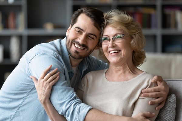 Smiling young man hug middle aged optimistic mother