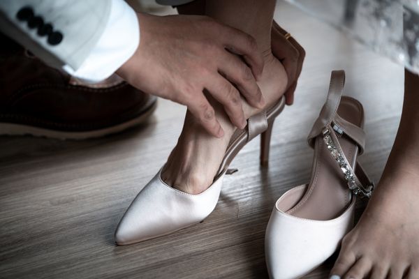 groom helps bride to put on shoes