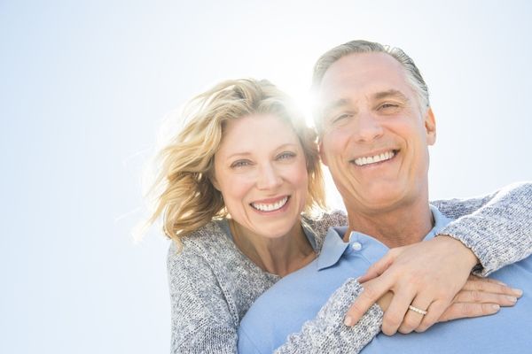 cheerful mature woman embracing man from behind