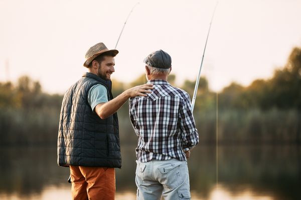 happy man talking to father while fishing