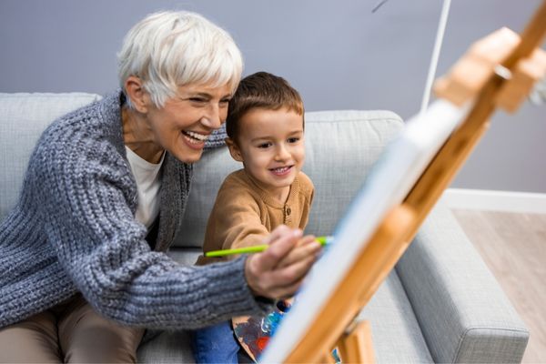 grandson grandma painting on canvas teaching how to paint