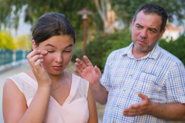 Girl teenager and her father quarrel outdoors