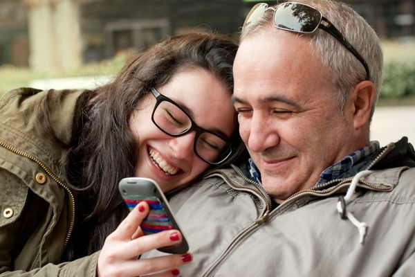 Father teenager daughter sharing funny mobile phone