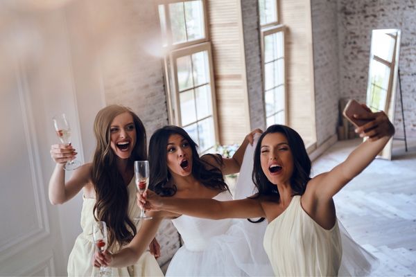 01 bride bridesmaids drinking champagne while taking selfie