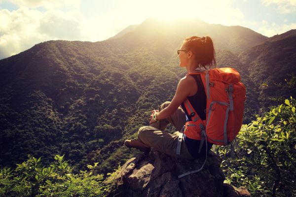 woman hiker enjoy sunset view on mountain peak cliff