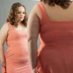 feature-female looking in mirror upset her belly calling herself fat
