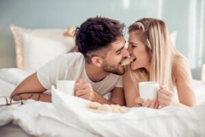 couple-each biting-one end of the same-bread-on-bed