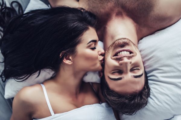 couple lying bed girl kiss cheek of partner upside down