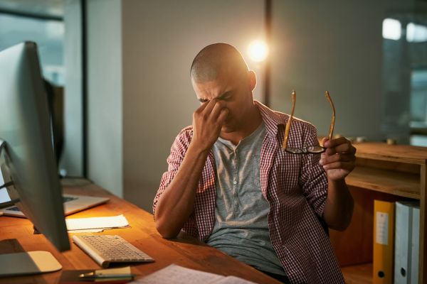 Man stressed hold nose in front of computer working struggling