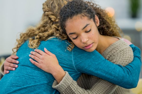 teen friends hugging saying good byes in sadness