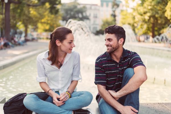 couple first date in a park fountain asking questions flirty