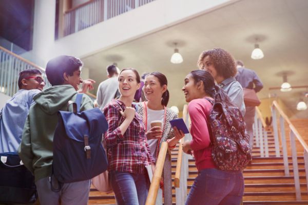 multi racial students chatting with joy on staircases in college school