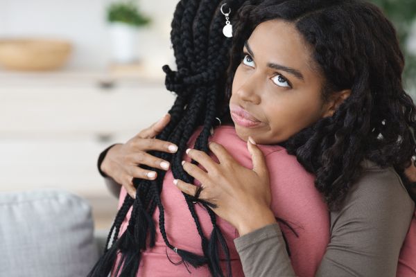 Irritated black lady hugging her girlfriend fake friendship