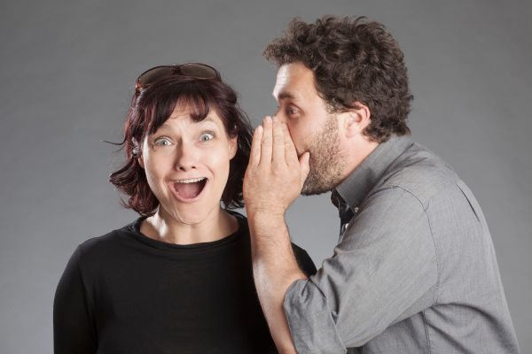 man whisper woman shocked open mouth