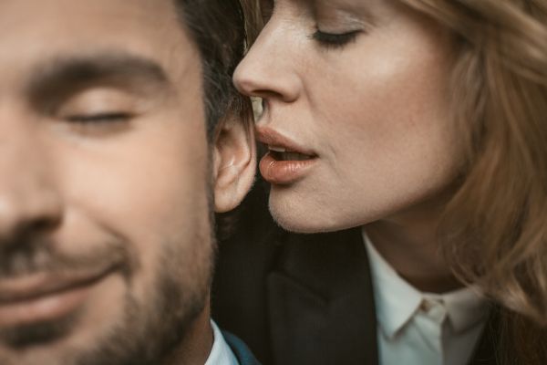 woman whispering a secret to a mans ear enjoy fun